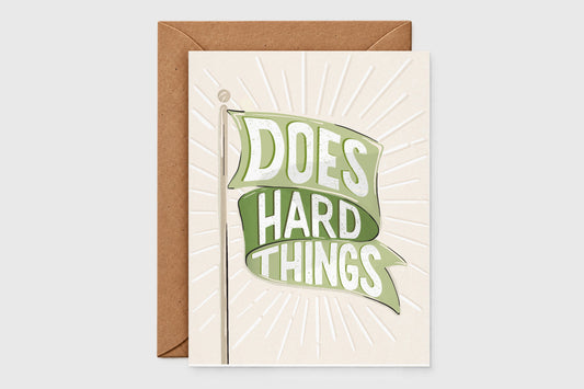 'Does Hard Things' green flag encouragement card with a green banner over an embossed sunburst