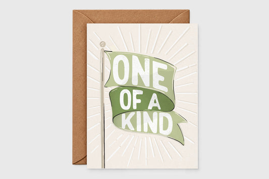 'One of a Kind' green flag card with a green banner over an embossed sunburst on cream