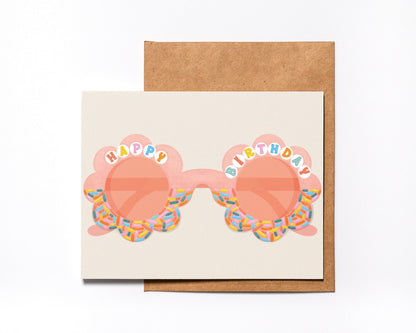 Happy Birthday card with peach flower-shaped sunglasses and rainbow sprinkle frames, with kraft envelope