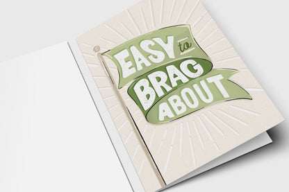 'Easy to Brag About' green flag card with a green banner over an embossed sunburst on cream