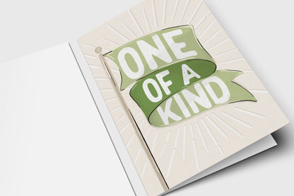 'One of a Kind' green flag card with a green banner over an embossed sunburst on cream