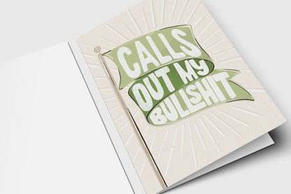 'Calls Out My Bullshit' green flag card with a green banner over an embossed sunburst on cream