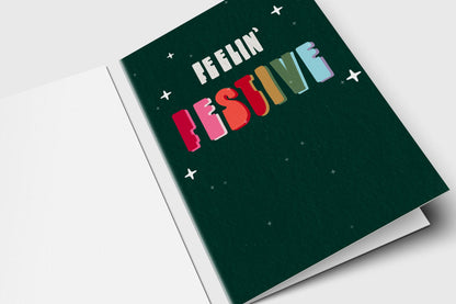Feelin' Festive holiday card with retro rainbow lettering and sparkles on dark green