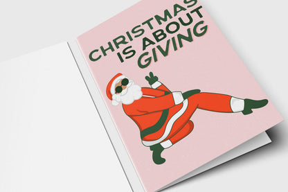 Funny Santa Christmas card reading 'Christmas is about giving' with Santa in sunglasses on pink