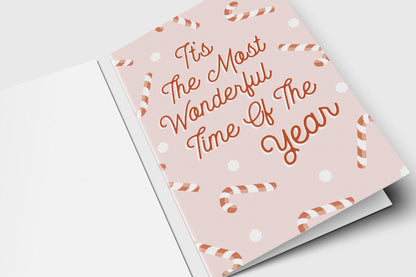Most Wonderful Time of the Year holiday card with rust script and candy canes on soft pink