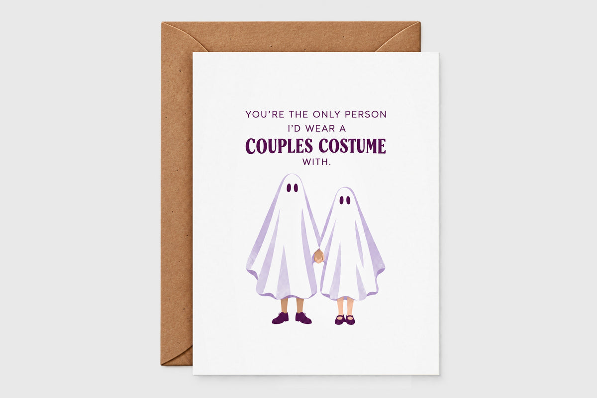 Couples costume Halloween card with an illustrated ghost couple holding hands on a white card with purple lettering, with kraft envelope