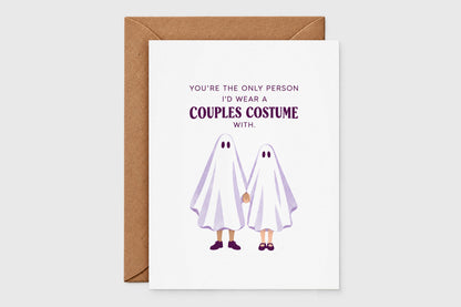 Couples costume Halloween card with an illustrated ghost couple holding hands on a white card with purple lettering, with kraft envelope